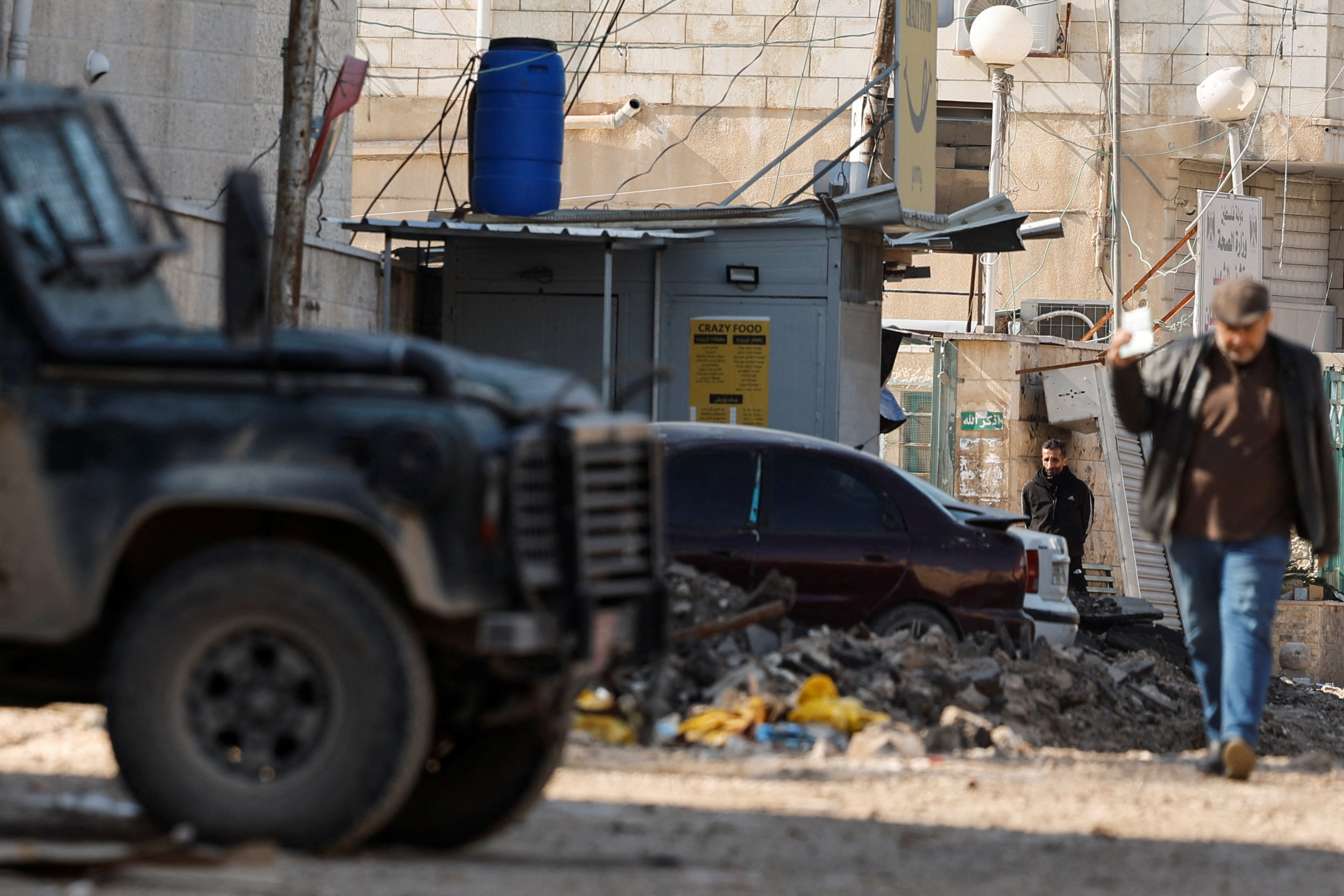 A man walks next to an Israeli military vehicle, in Jenin