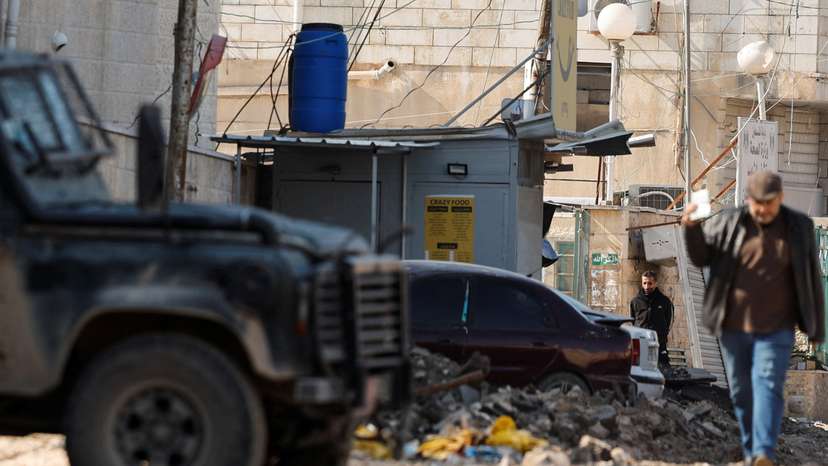A man walks next to an Israeli military vehicle, in Jenin
