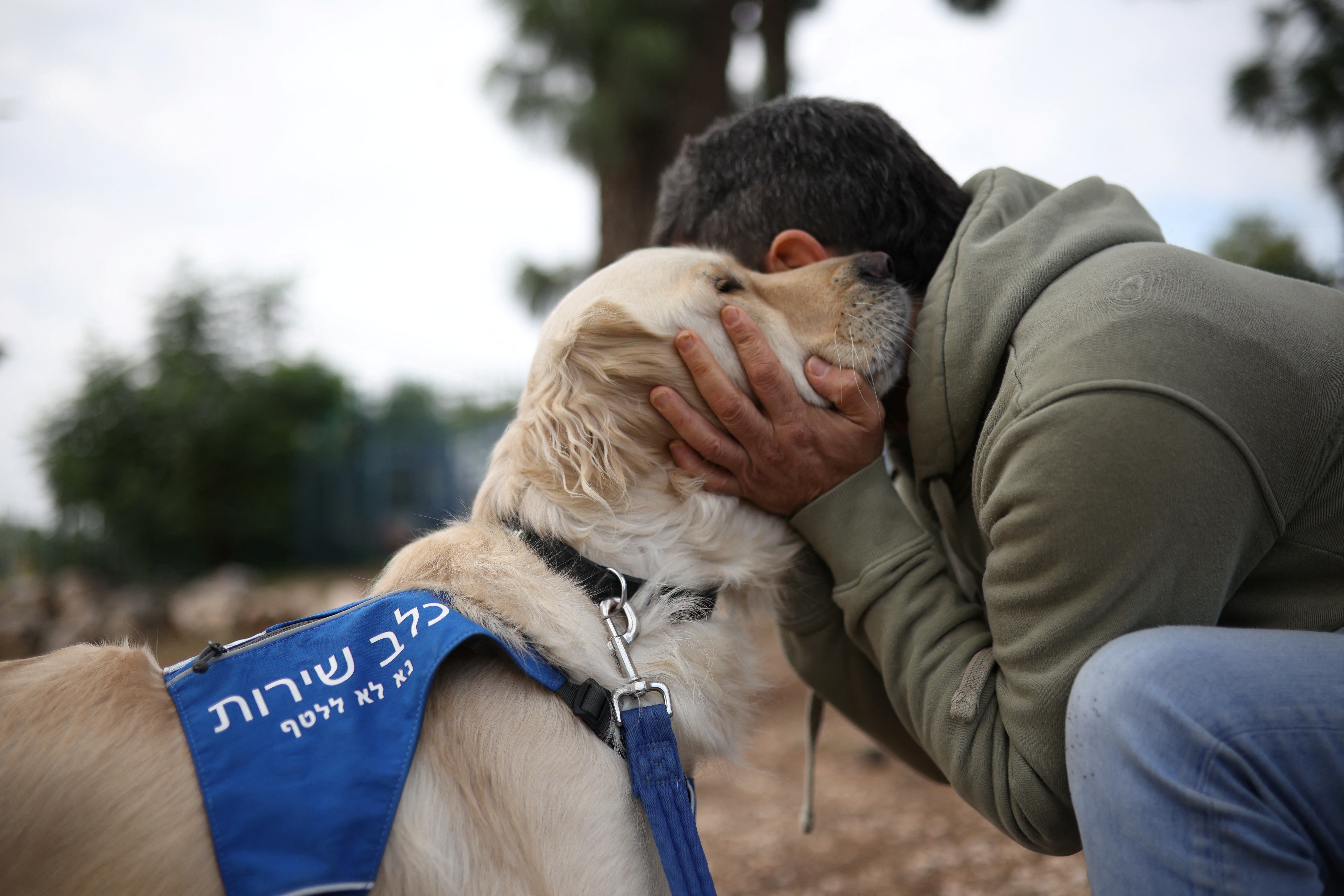 A former soldier being treated for PTSD at the Combat Veterans Psychedelic Research Clinic at Emek Medical Center, embraces his service dog, in Afula