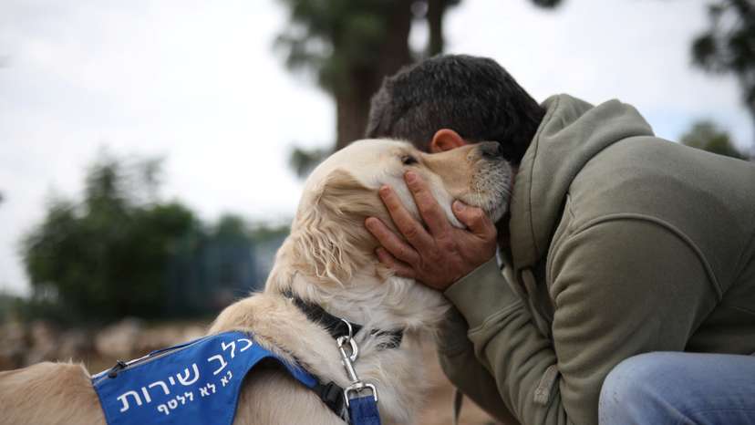 A former soldier being treated for PTSD at the Combat Veterans Psychedelic Research Clinic at Emek Medical Center, embraces his service dog, in Afula