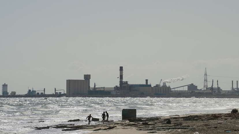 Children play on the beach with the Tunisian Chemical Group’s (CGT) phosphate complex visible in the background, in Gabes