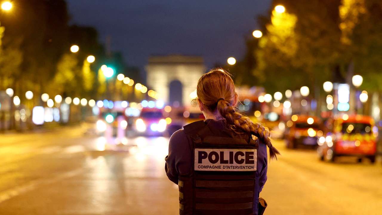 FILE PHOTO: A Police officer stands guard on the Champs Elysees avenue, next to the Arc de Triomphe