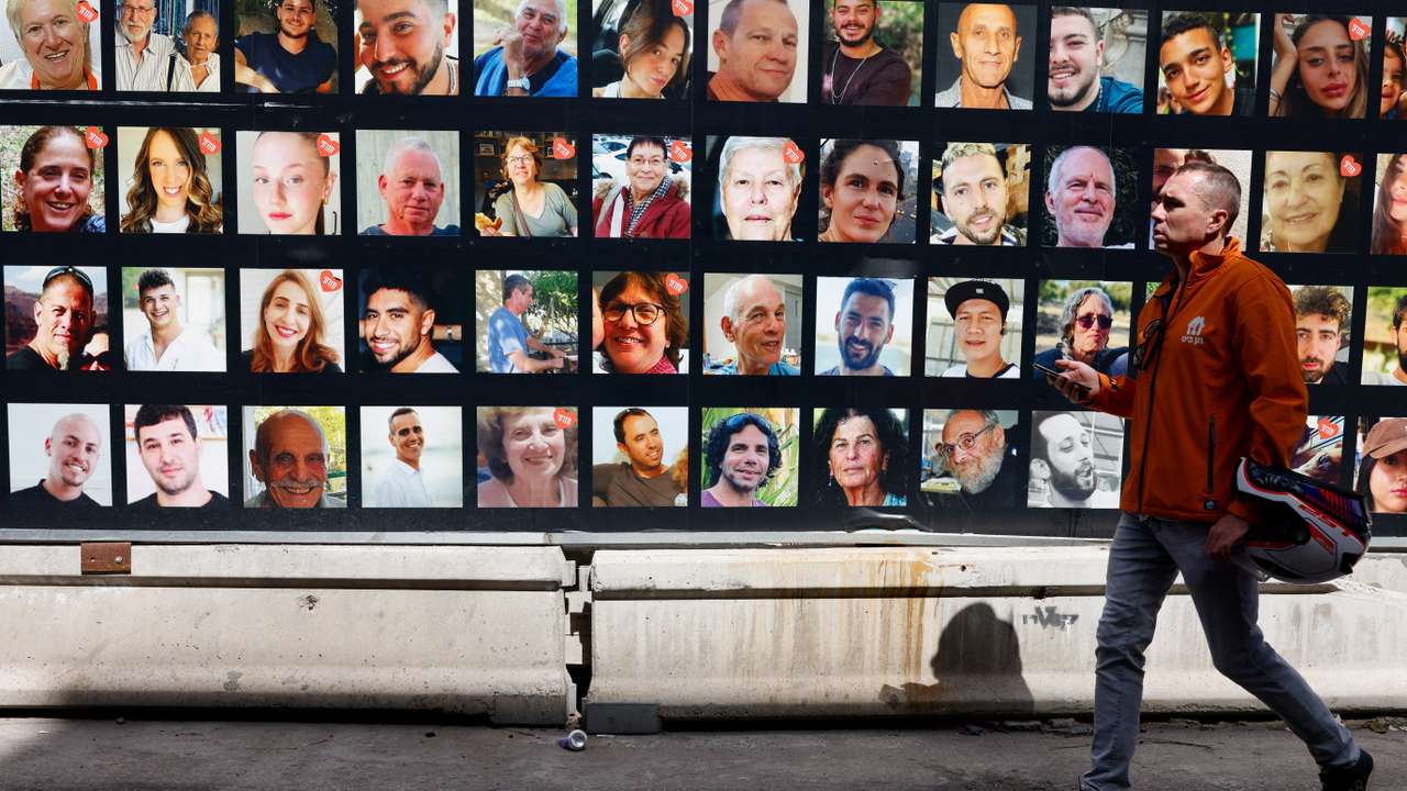 People walk past photos of hostages who were kidnapped in the deadly October 7 attack, in Tel Aviv