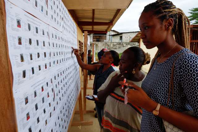 People look for their name on the electoral roll, ahead of the 2025 Gabonese presidential electionat a polling station in Lambarene