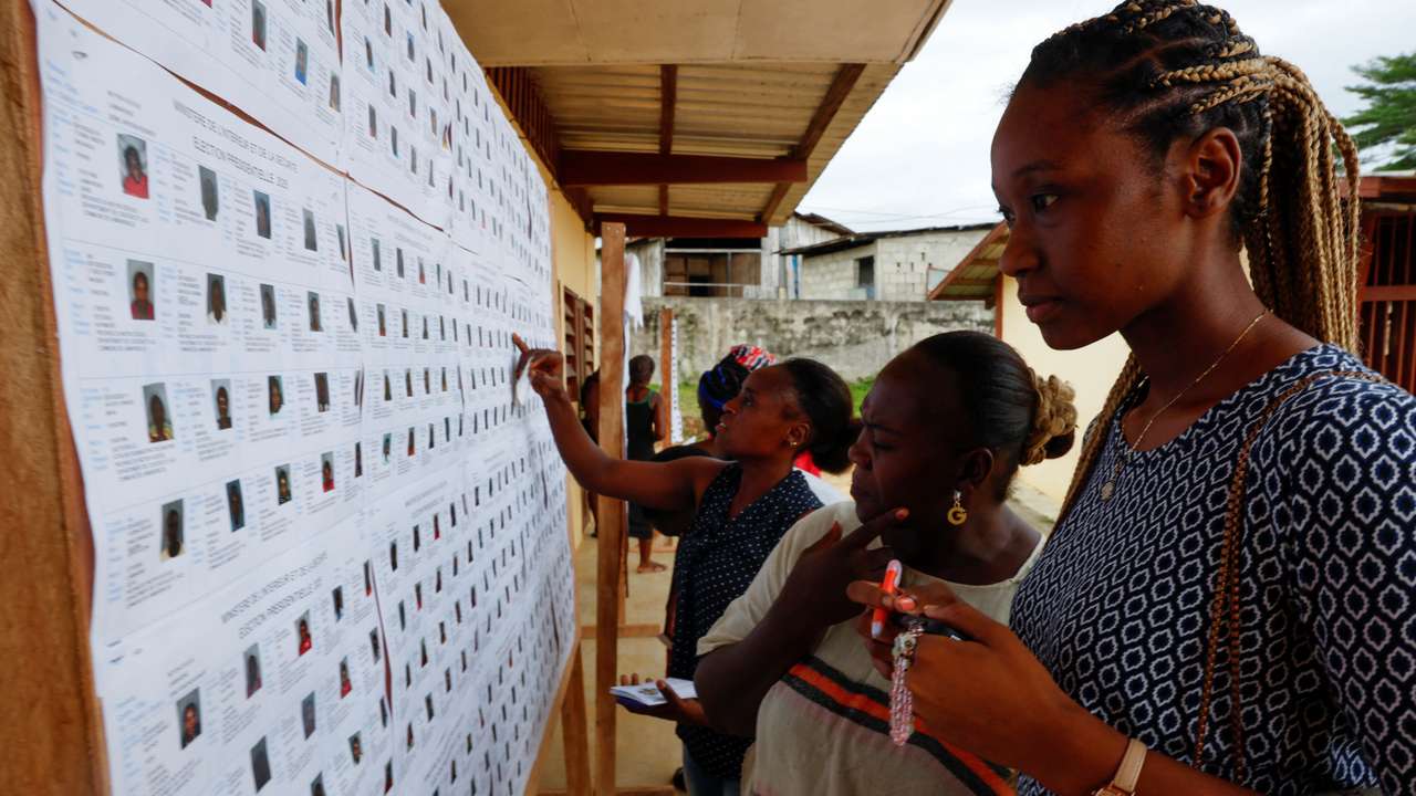 People look for their name on the electoral roll, ahead of the 2025 Gabonese presidential electionat a polling station in Lambarene