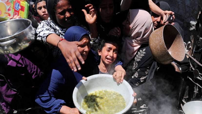 FILE PHOTO: Palestinians receive food cooked by a charity kitchen, in Beit Lahia