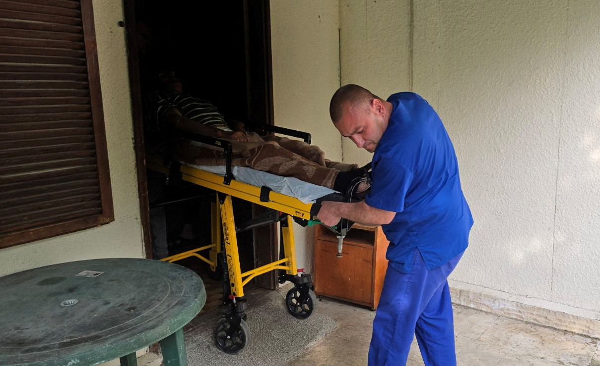 Medic transports an elderly person on a stretcher outside an illegal hospice in the village of Yagoda