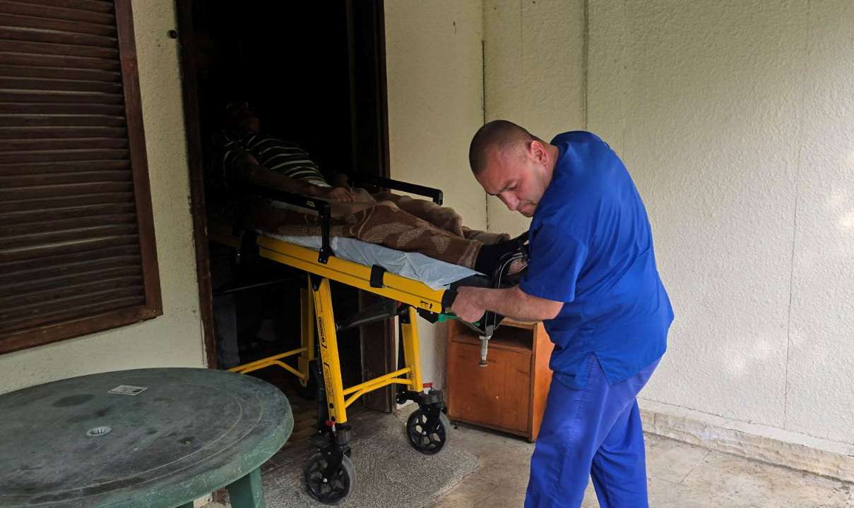 Medic transports an elderly person on a stretcher outside an illegal hospice in the village of Yagoda