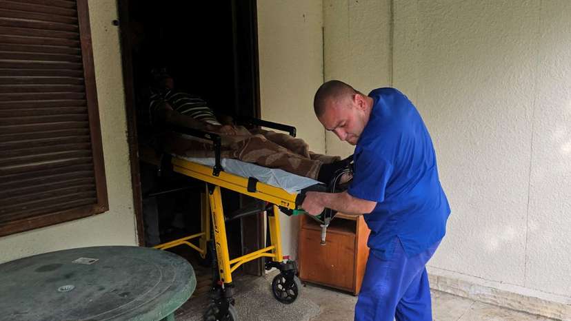 Medic transports an elderly person on a stretcher outside an illegal hospice in the village of Yagoda