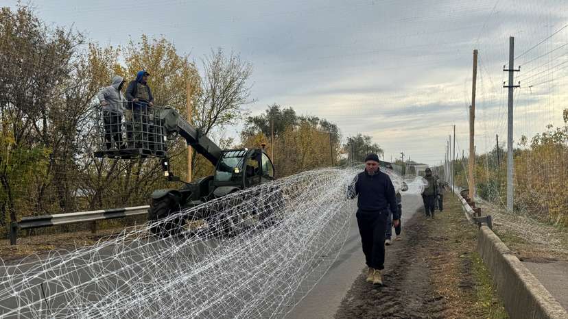 Ukrainian servicemen install anti-drone nets over a road near the frontline town of Dobropillia
