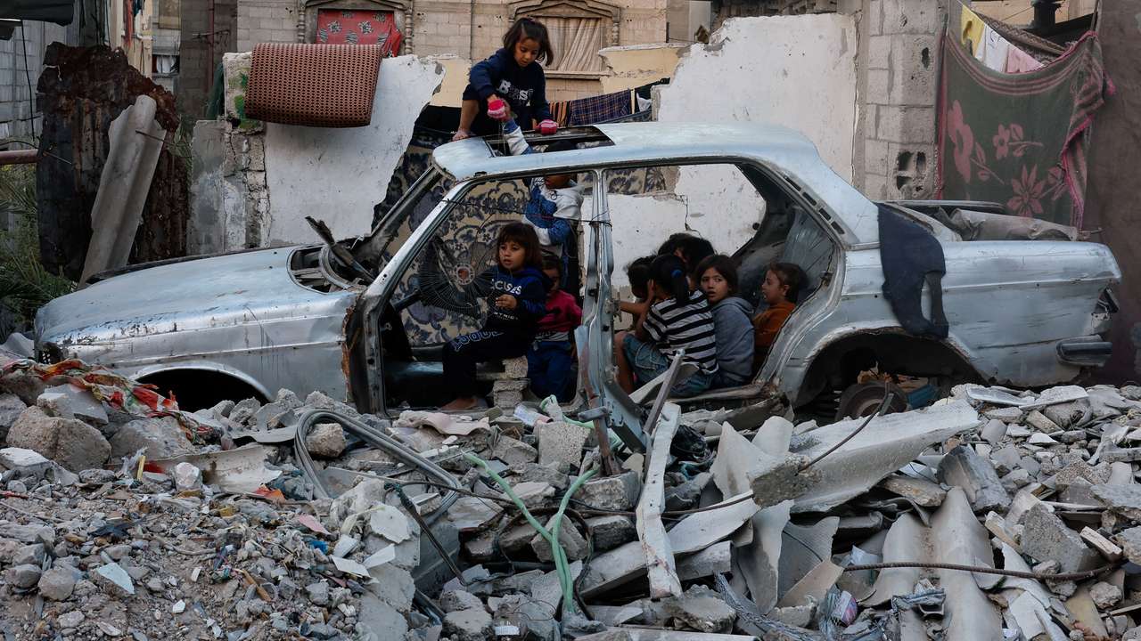 Palestinian children gather at a destroyed vehicle in Khan Younis