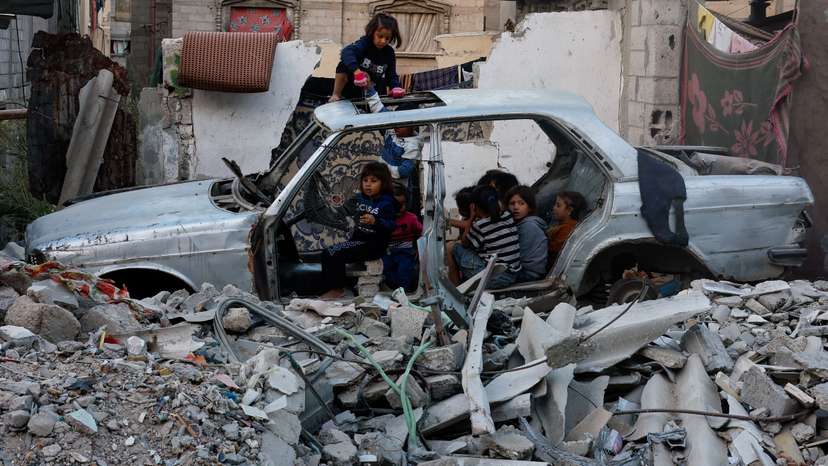 Palestinian children gather at a destroyed vehicle in Khan Younis