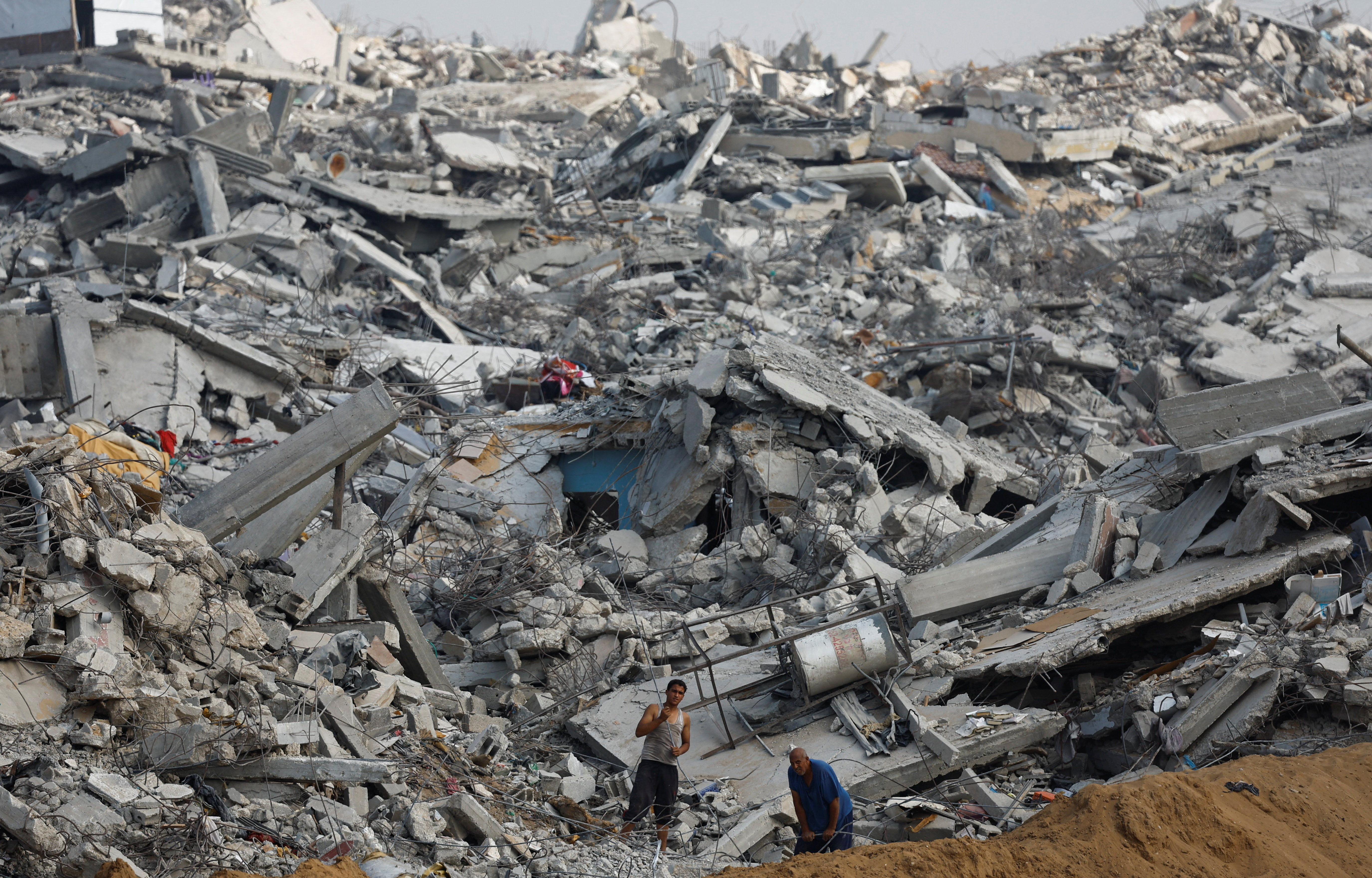 Palestinians work amid the rubble of destroyed buildings, during a ceasefire between Israel and Hamas, in Jabalia