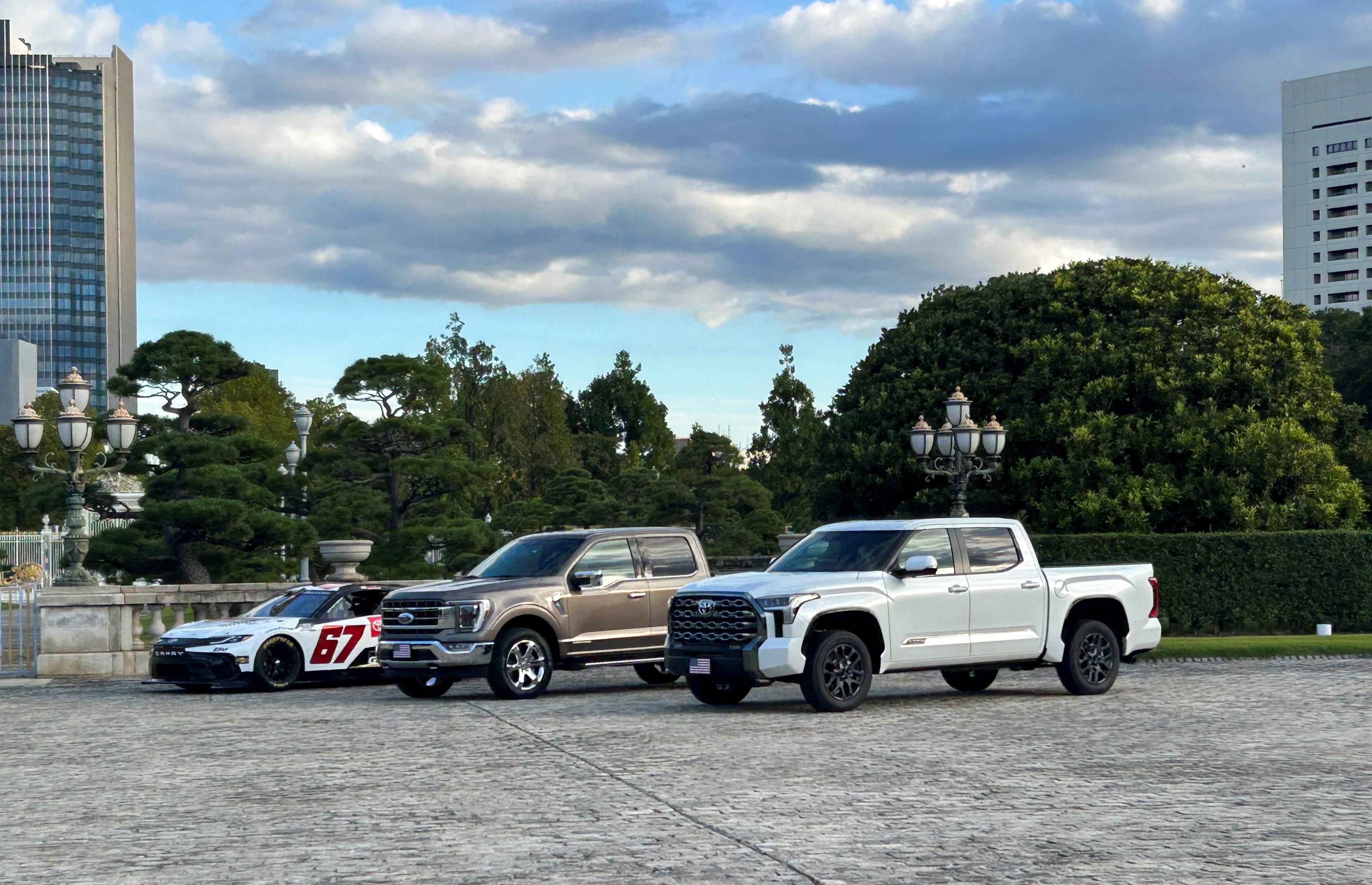 A Ford F-150 and a Toyota pickup truck are parked outside of Akasaka Palace, in Tokyo