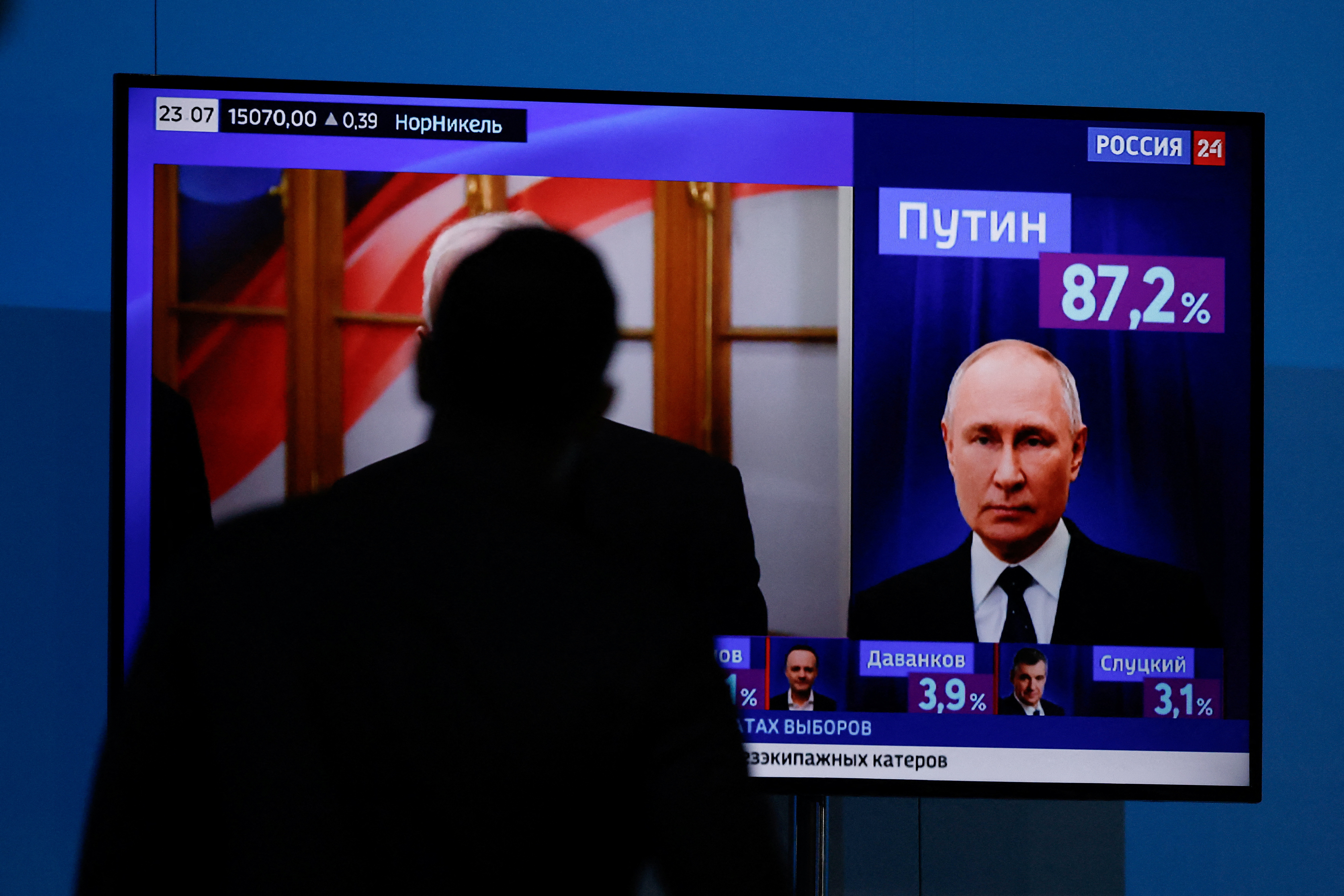 A man watches a TV broadcasting news on the results of Russian incumbent President and presidential candidate Vladimir Putin, in Moscow