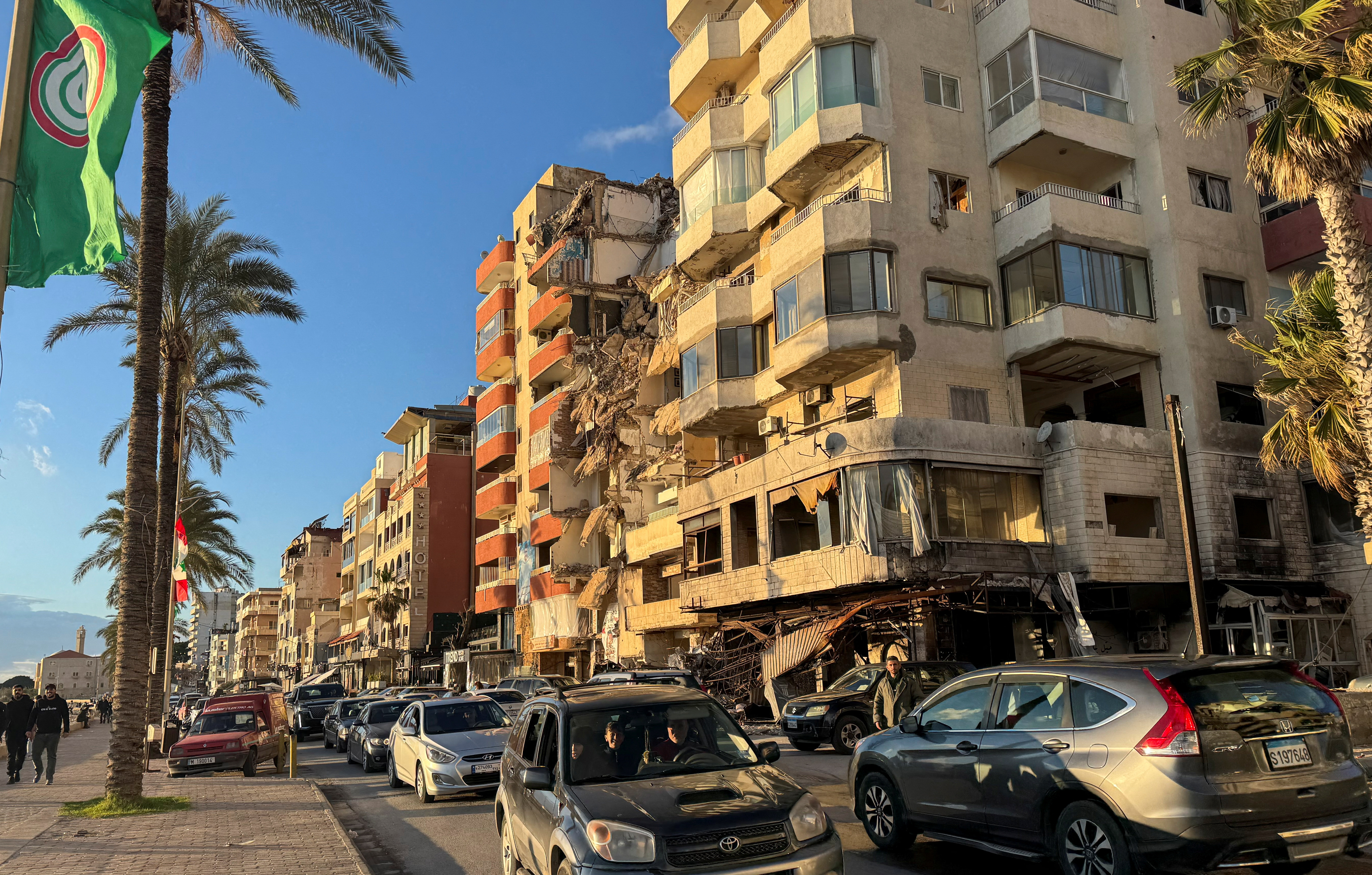 Cars drive past a damaged building near the Corniche, in Tyre