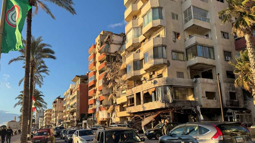 Cars drive past a damaged building near the Corniche, in Tyre