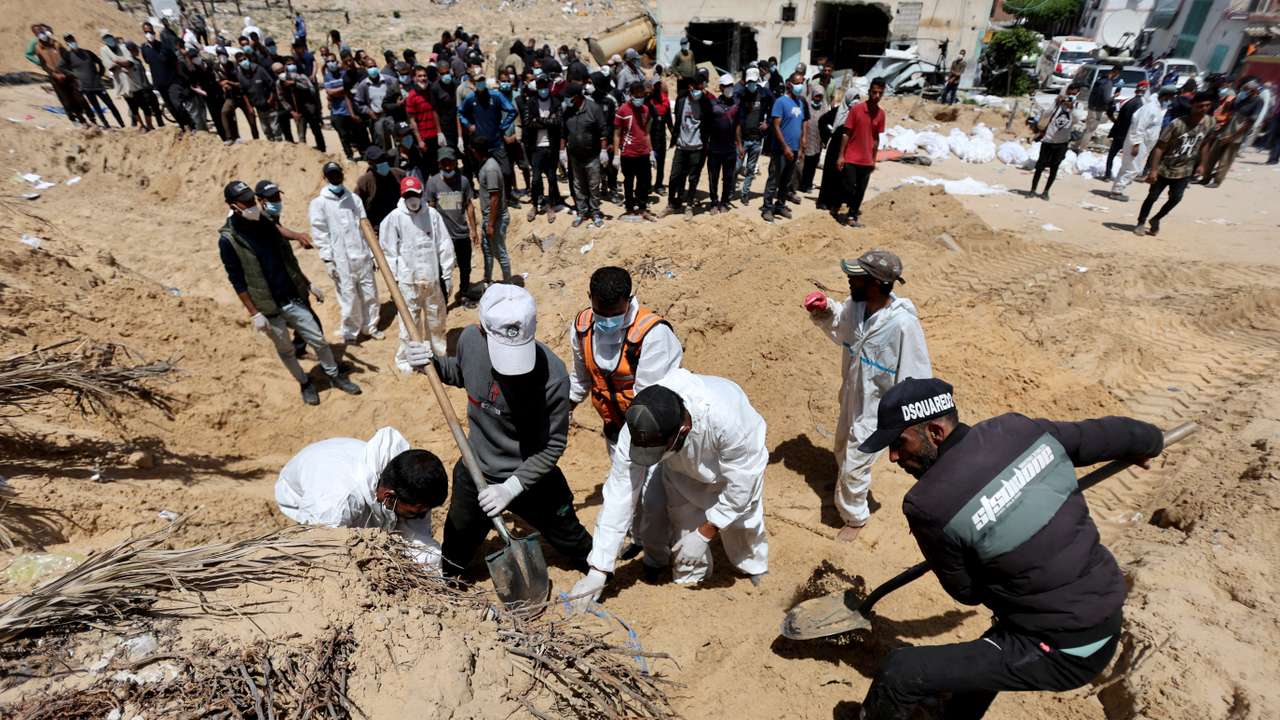 People work to move into a cemetery bodies of Palestinians killed during Israel's military offensive and buried at Nasser hospital, in Khan Younis