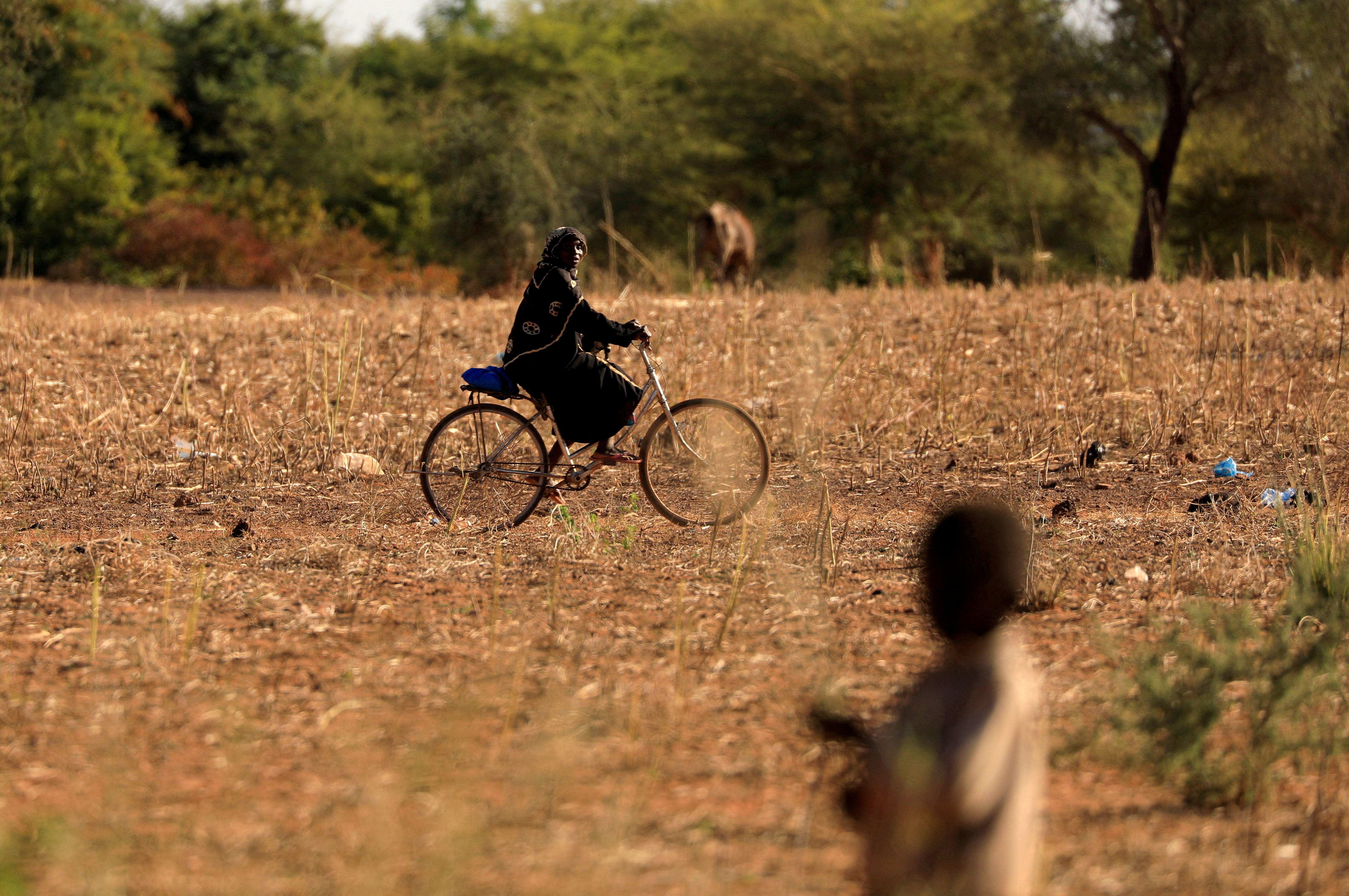 FILE PHOTO: A child and bicycle-riding woman are pictured at a camp for internally displaced people (IDPs) in Kaya