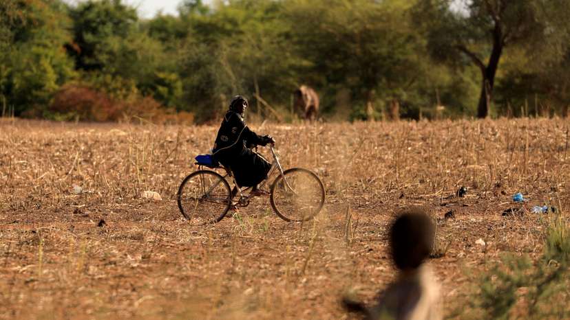 FILE PHOTO: A child and bicycle-riding woman are pictured at a camp for internally displaced people (IDPs) in Kaya