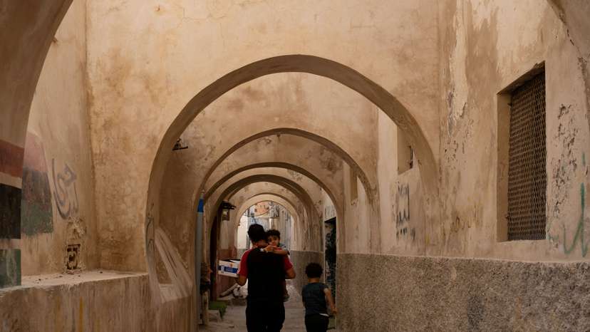 FILE PHOTO: A man walks with his son in the old city of Tripoli