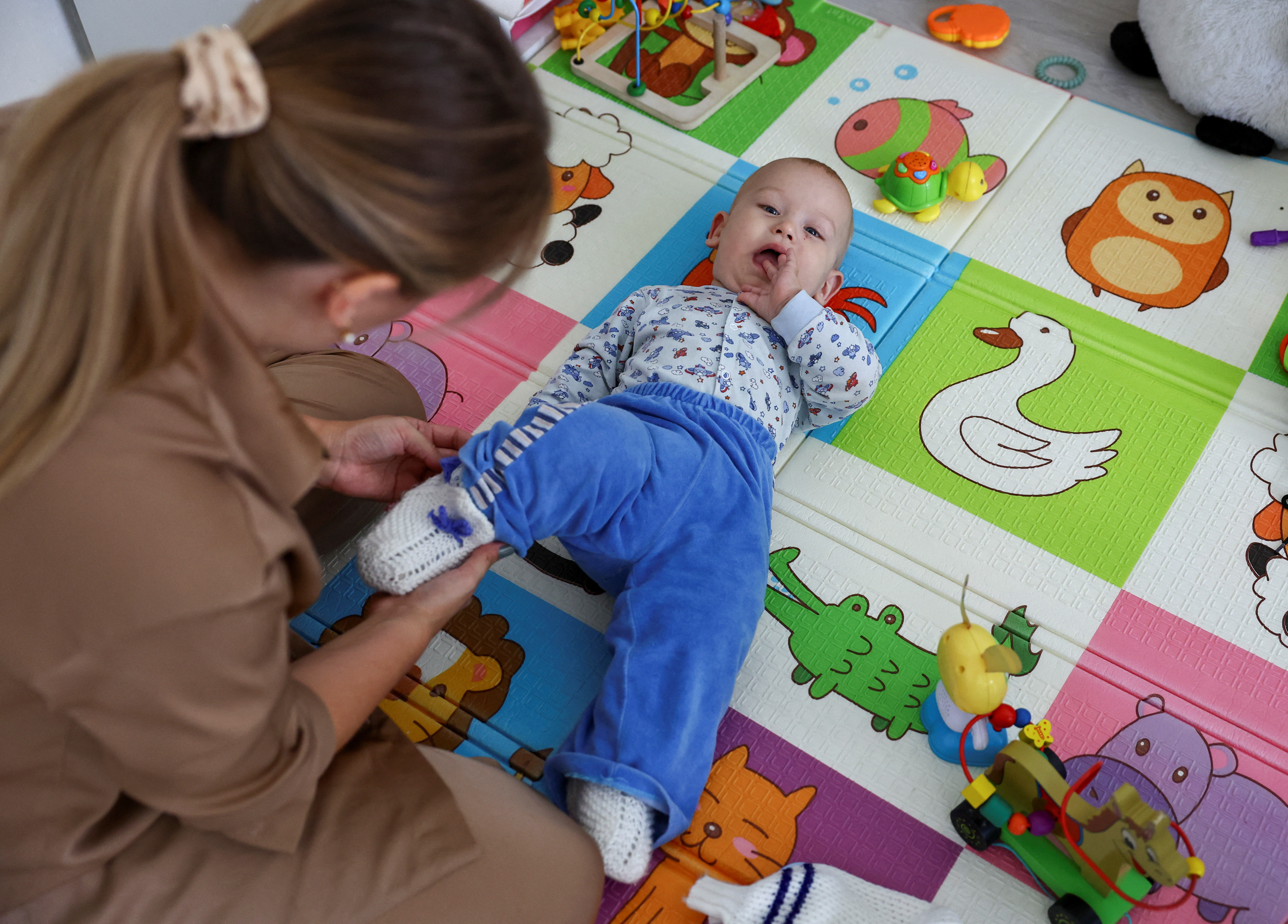 Alina Rzhanova adjusts clothes of her son Igor during an interview in their apartment in Yaroslavl