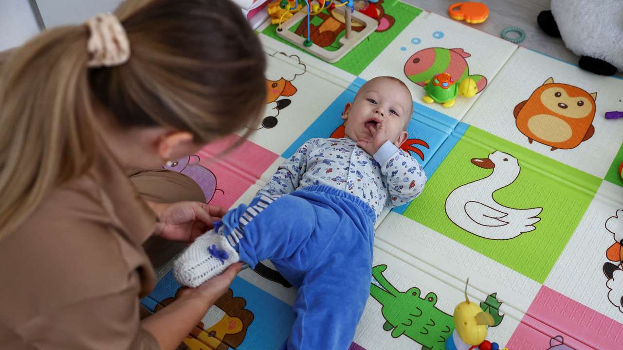 Alina Rzhanova adjusts clothes of her son Igor during an interview in their apartment in Yaroslavl