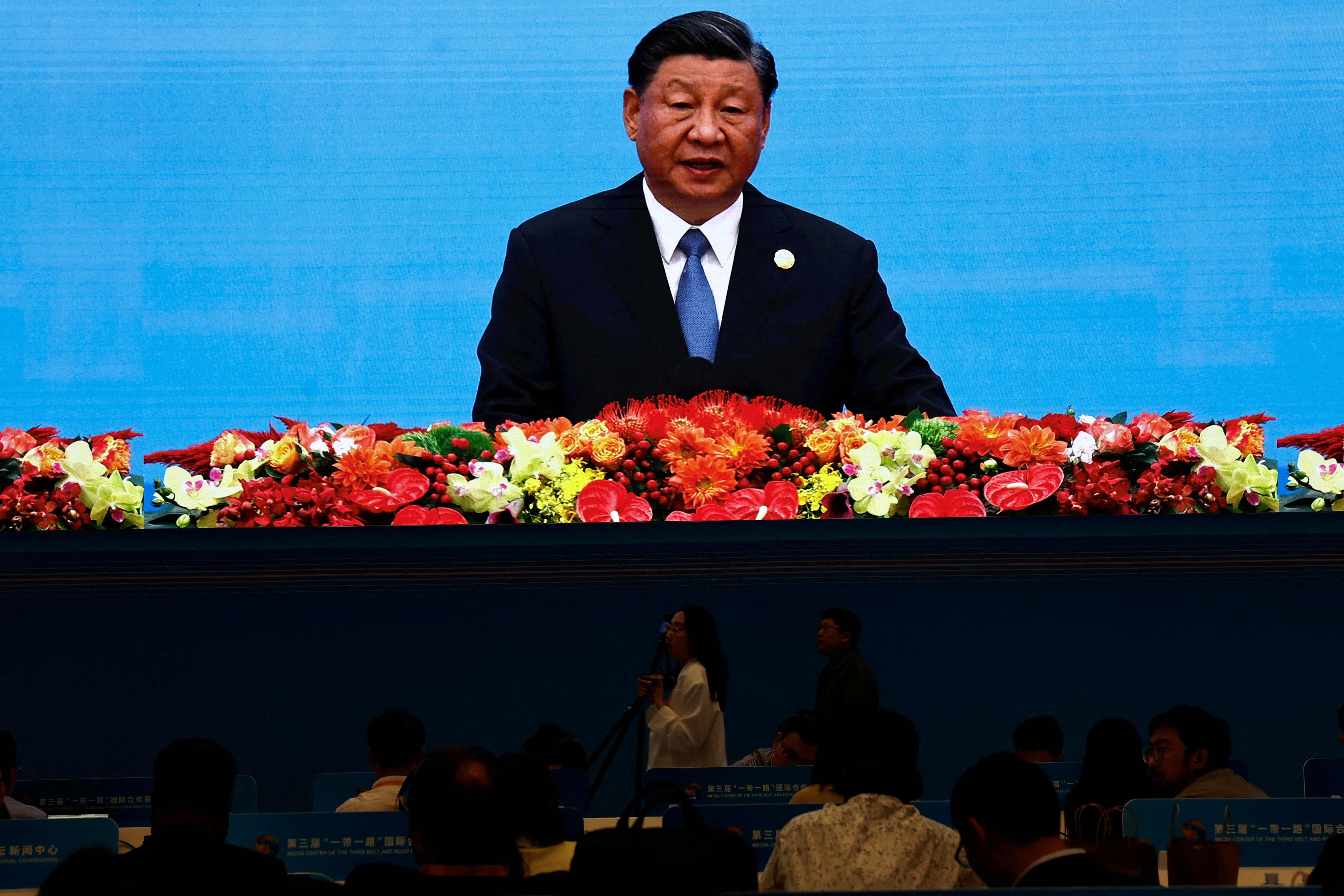 FILE PHOTO: Journalists watch a giant screen broadcasting footage of Chinese President Xi Jinping at the opening ceremony of BRF in Beijing