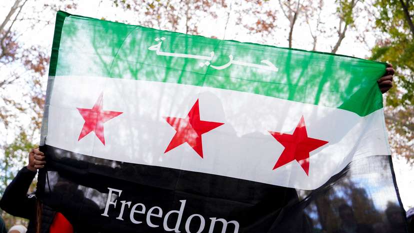 A person holds a Syrian opposition flag during a demonstration celebrating the fall of Bashar Al-Assad regime outside the Syrian embassy in Madrid