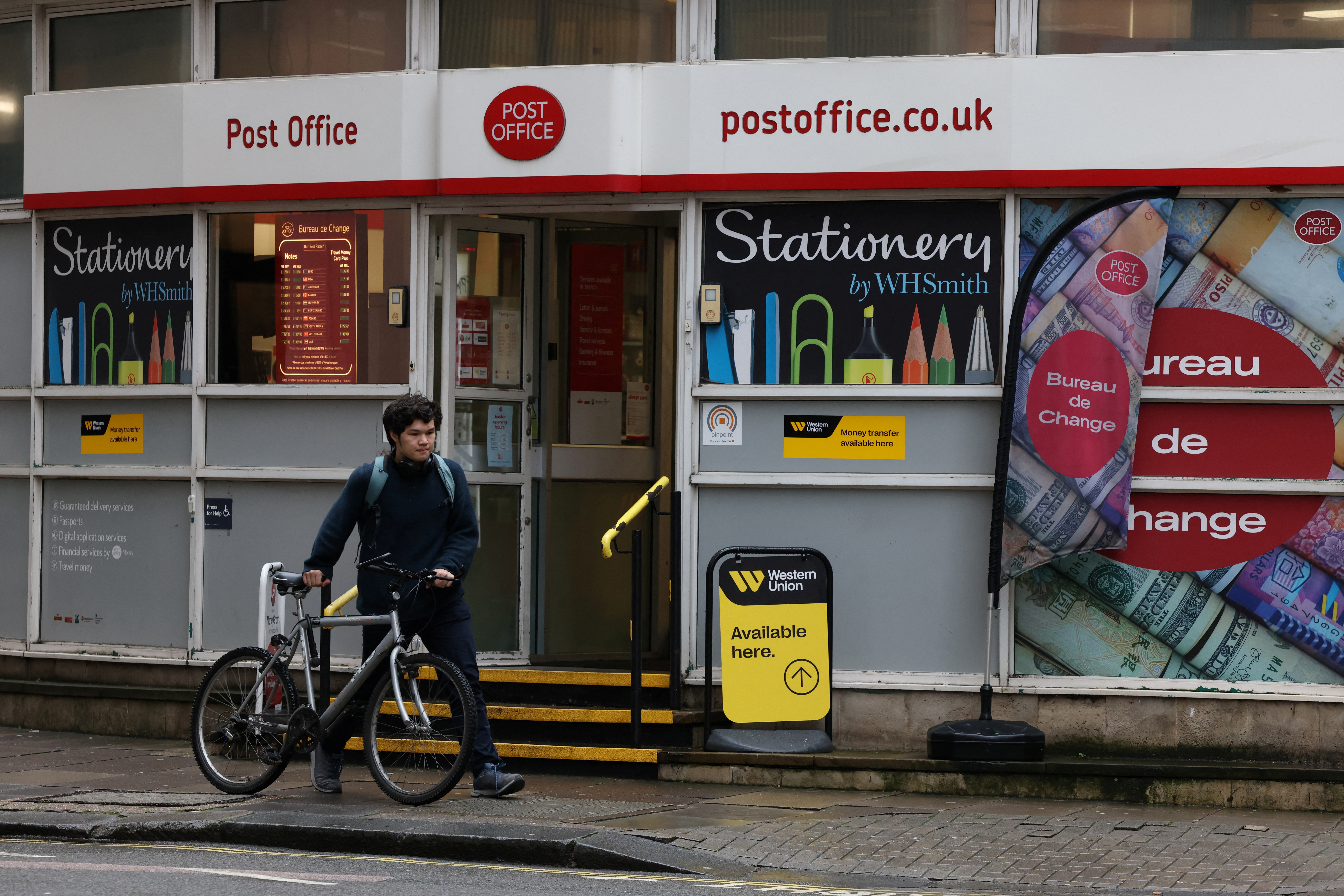 A cyclist walks past a Post Office branch in Westminster