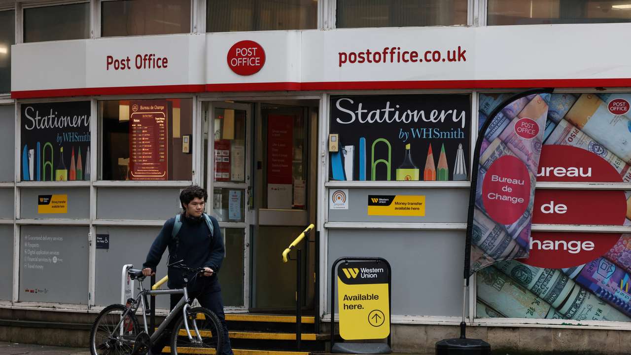 A cyclist walks past a Post Office branch in Westminster