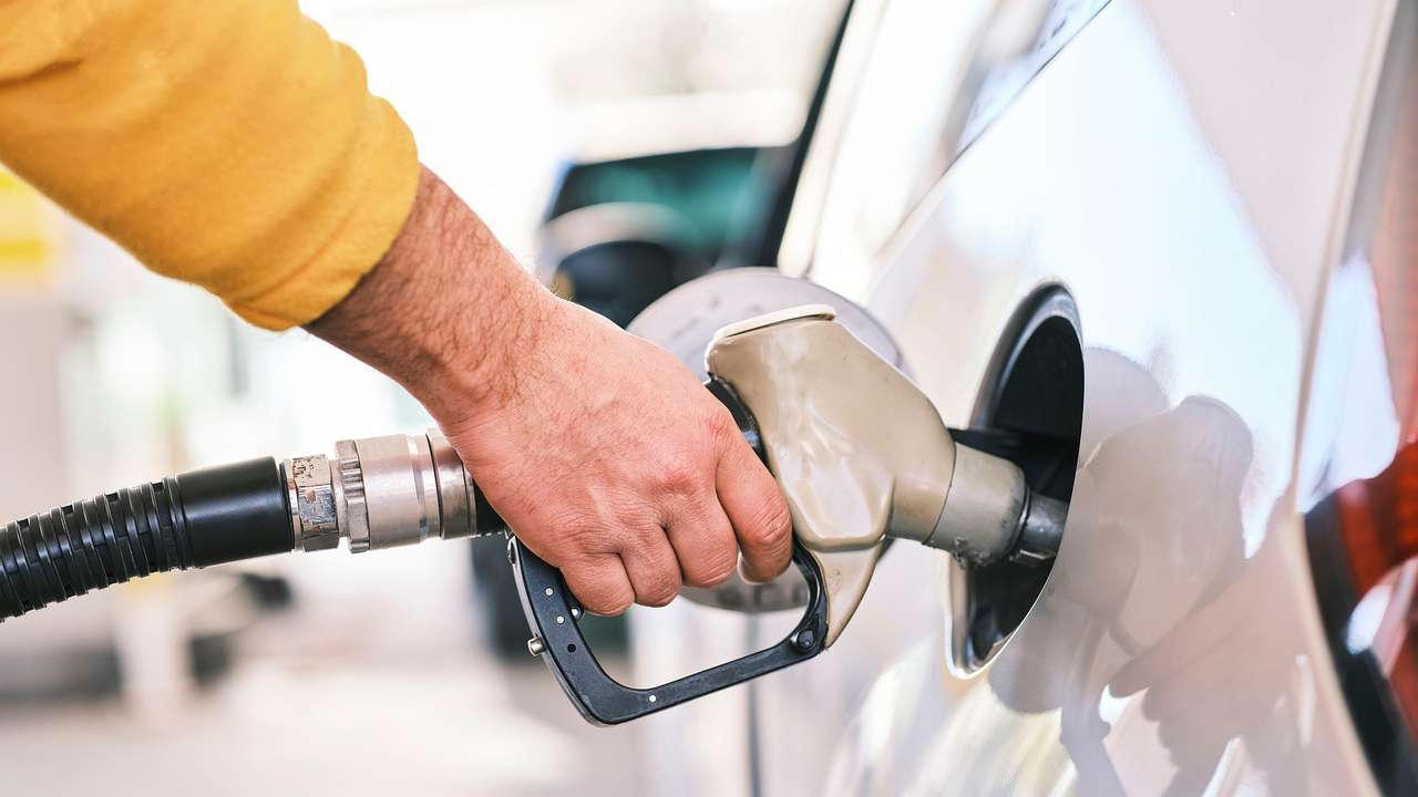 Mão segura bomba de gasolina para abastecer carro