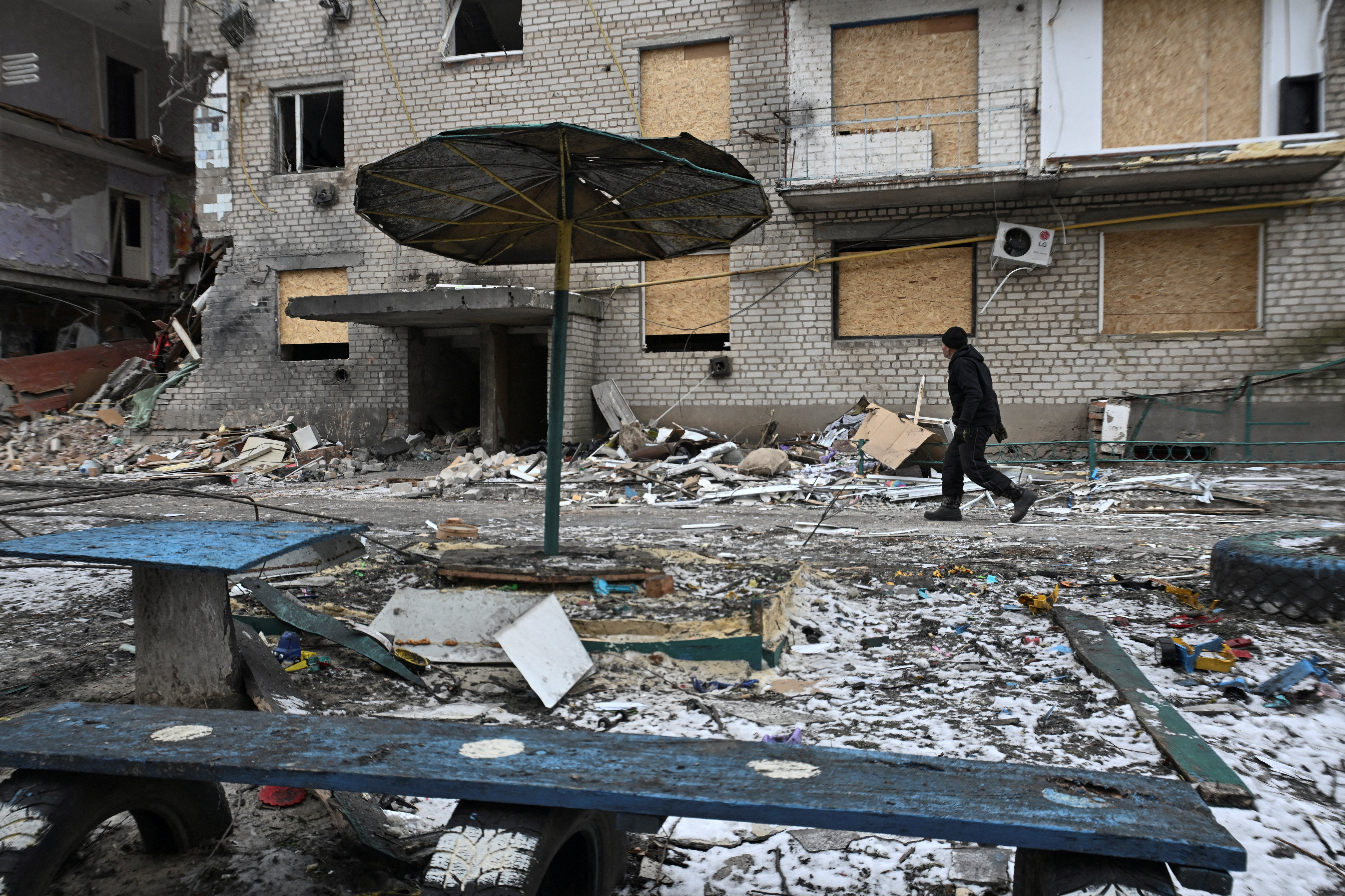 FILE PHOTO: Resident walks next to an apartment building damaged by Russian military strikes in the frontline town of Komyshuvakha