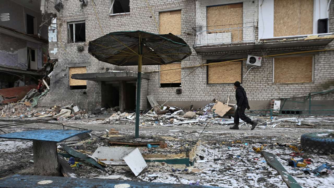 FILE PHOTO: Resident walks next to an apartment building damaged by Russian military strikes in the frontline town of Komyshuvakha