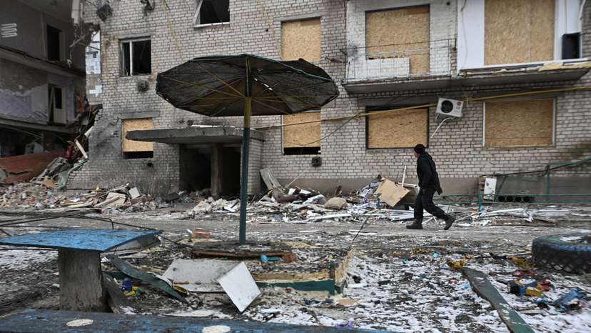 FILE PHOTO: Resident walks next to an apartment building damaged by Russian military strikes in the frontline town of Komyshuvakha
