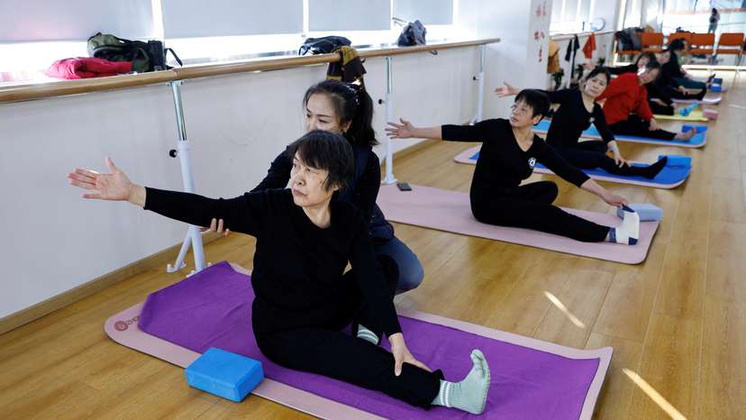 FILE PHOTO: A teacher coaches an elderly person during a yoga class in Beijing