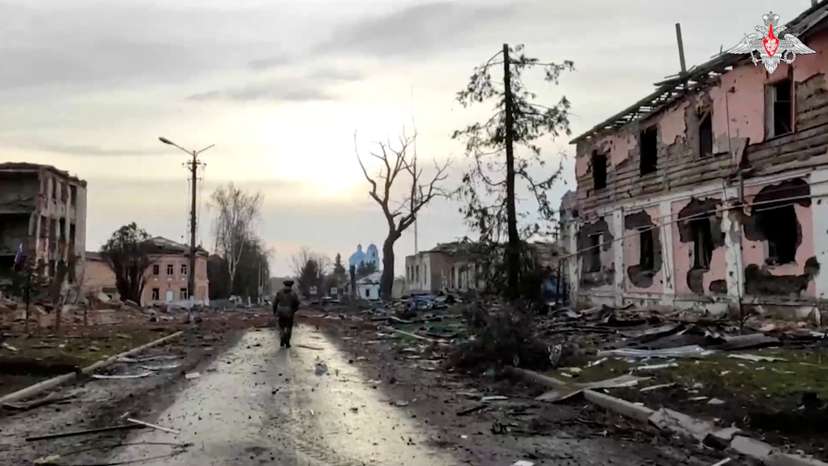A Russian service member walks past destroyed buildings in Sudzha