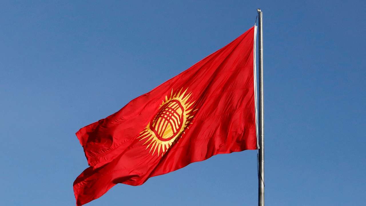 Honour guards march near the renewed Kyrgyz national flag during a ceremony in Bishkek