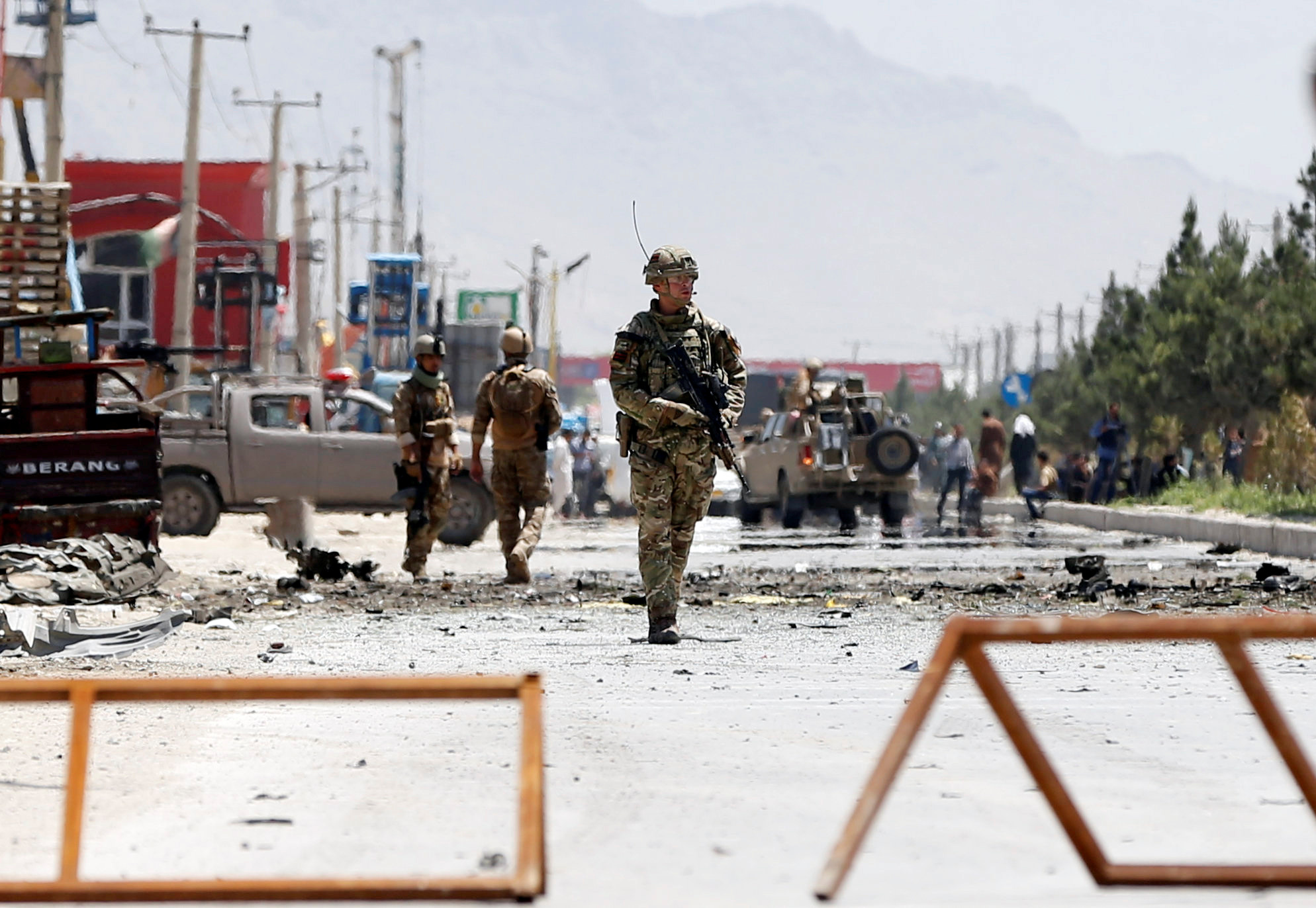 Afghan security forces and a British soldier with NATO-led Resolute Support Mission stand guard at the site of a suicide attack in Kabul