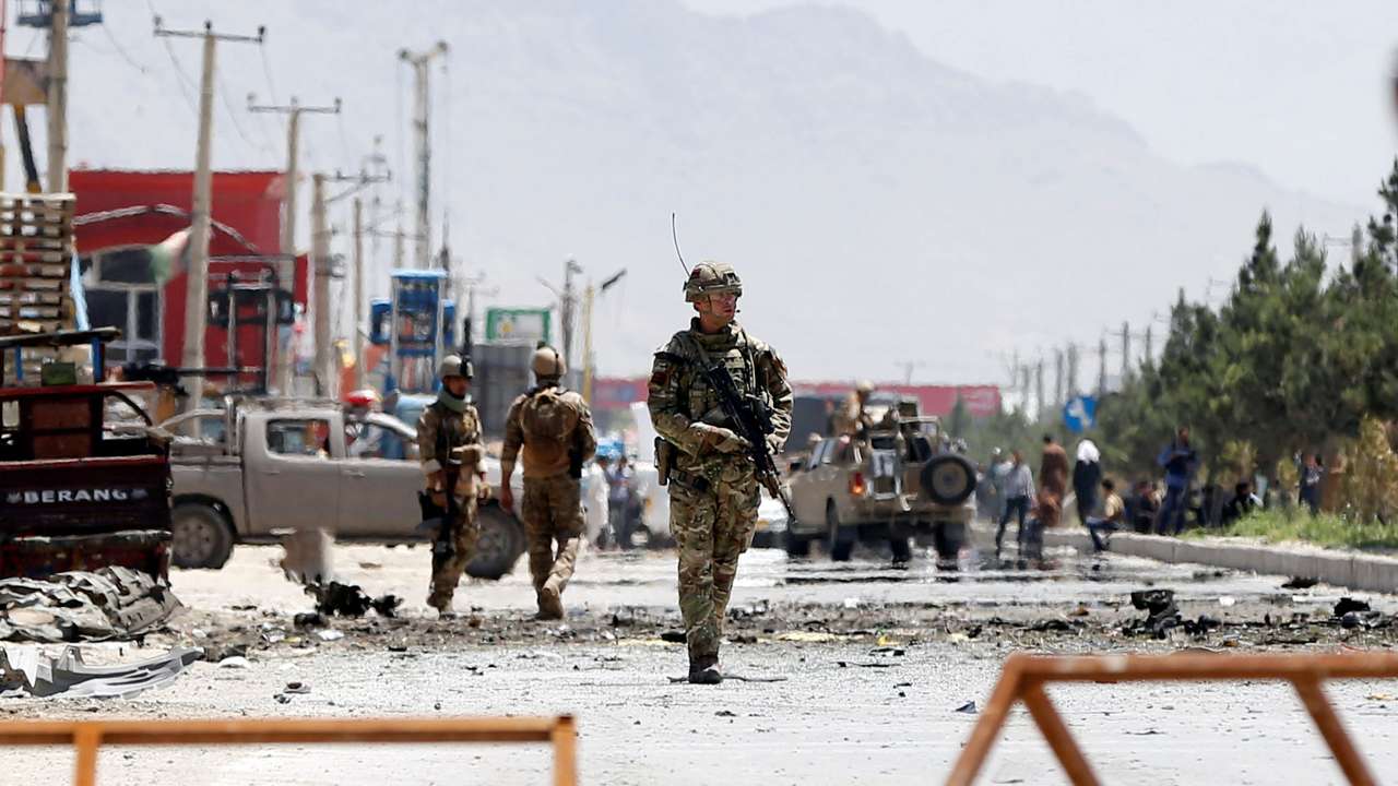 Afghan security forces and a British soldier with NATO-led Resolute Support Mission stand guard at the site of a suicide attack in Kabul