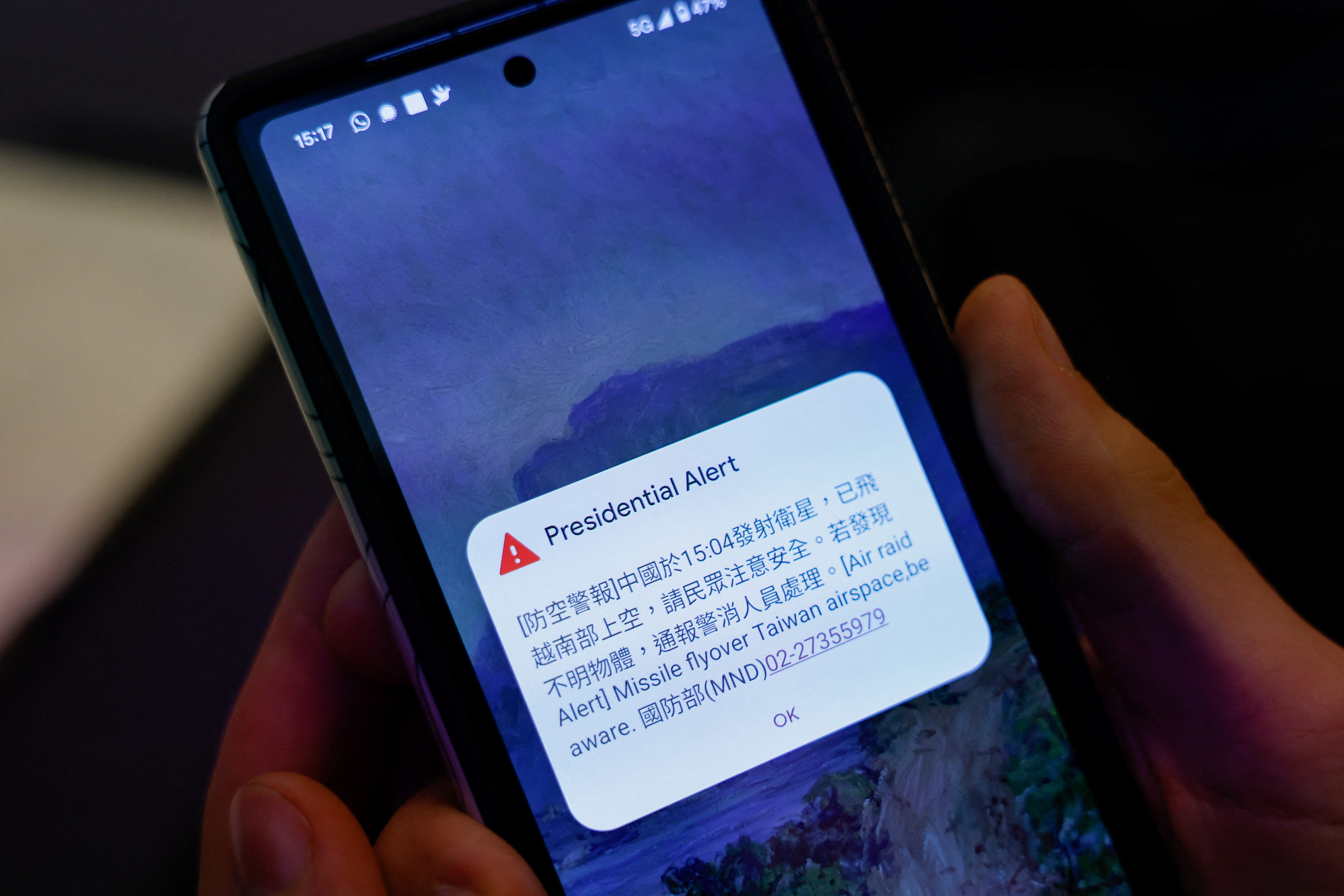 A person attending a Foreign Ministry's news conference holds a phone showing air raid alert about  a Chinese satellite