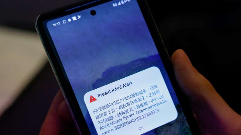 A person attending a Foreign Ministry's news conference holds a phone showing air raid alert about a Chinese satellite