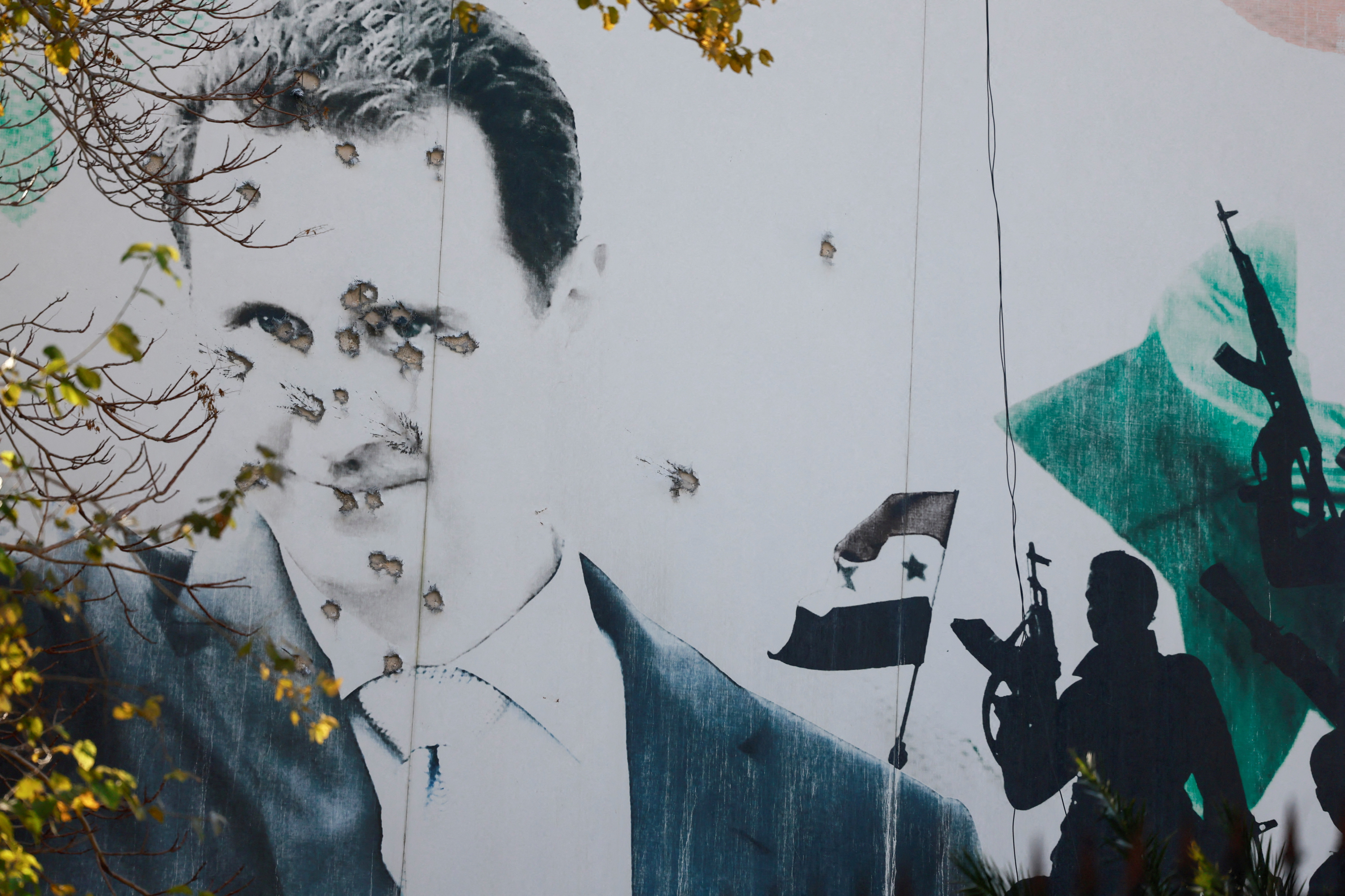 A billboard with a picture of Syria's Bashar al-Assad shows damage by bullet holes, after the ousting of Syria's Bashar al-Assad, in Damascus