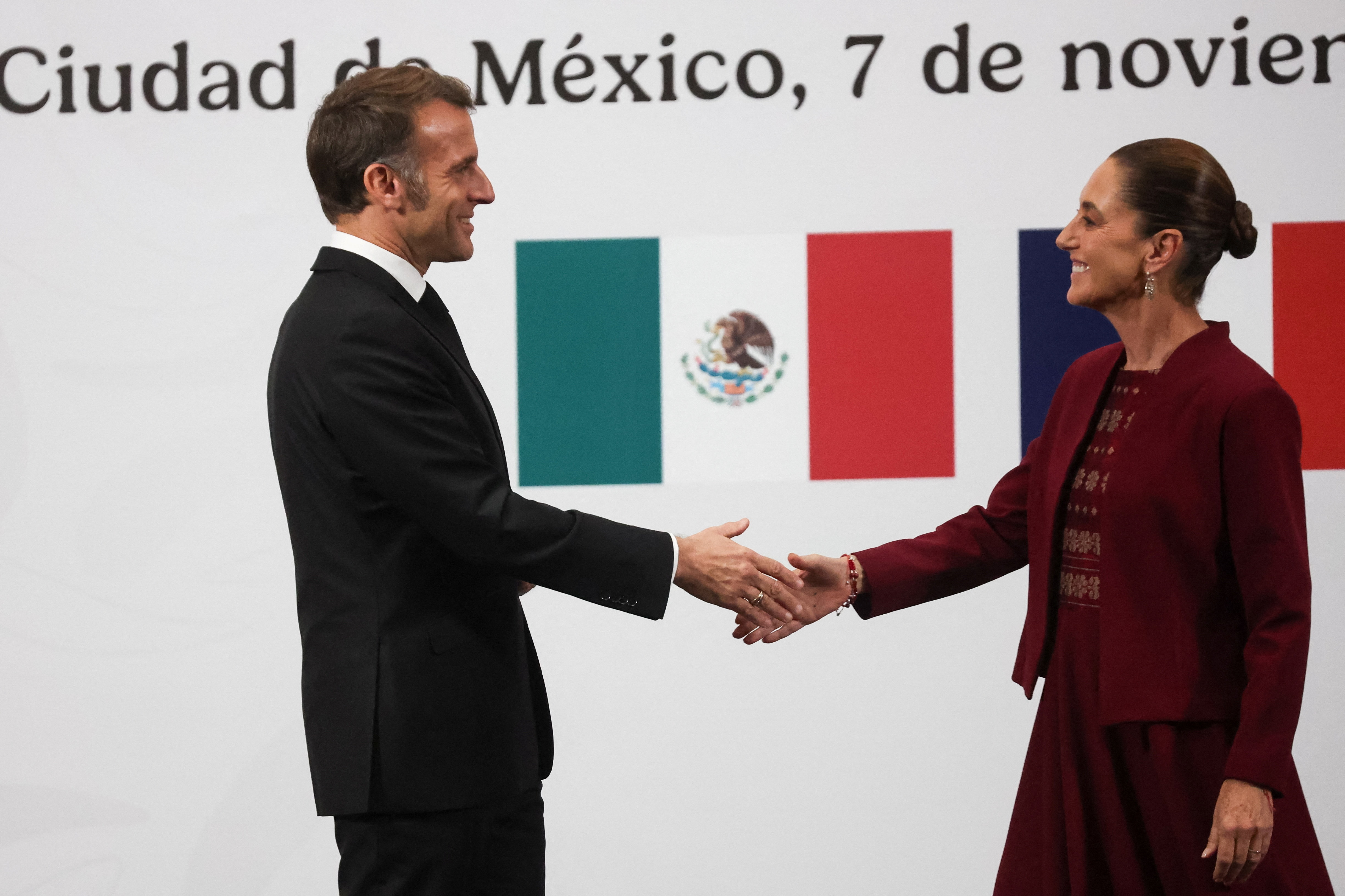Mexico's President Claudia Sheinbaum and France's President Emmanuel Macron reach out to shake hands as they attend a press conference at the National Palace in Mexico City, Mexico, November 7, 2025. REUTERS/Henry Romero