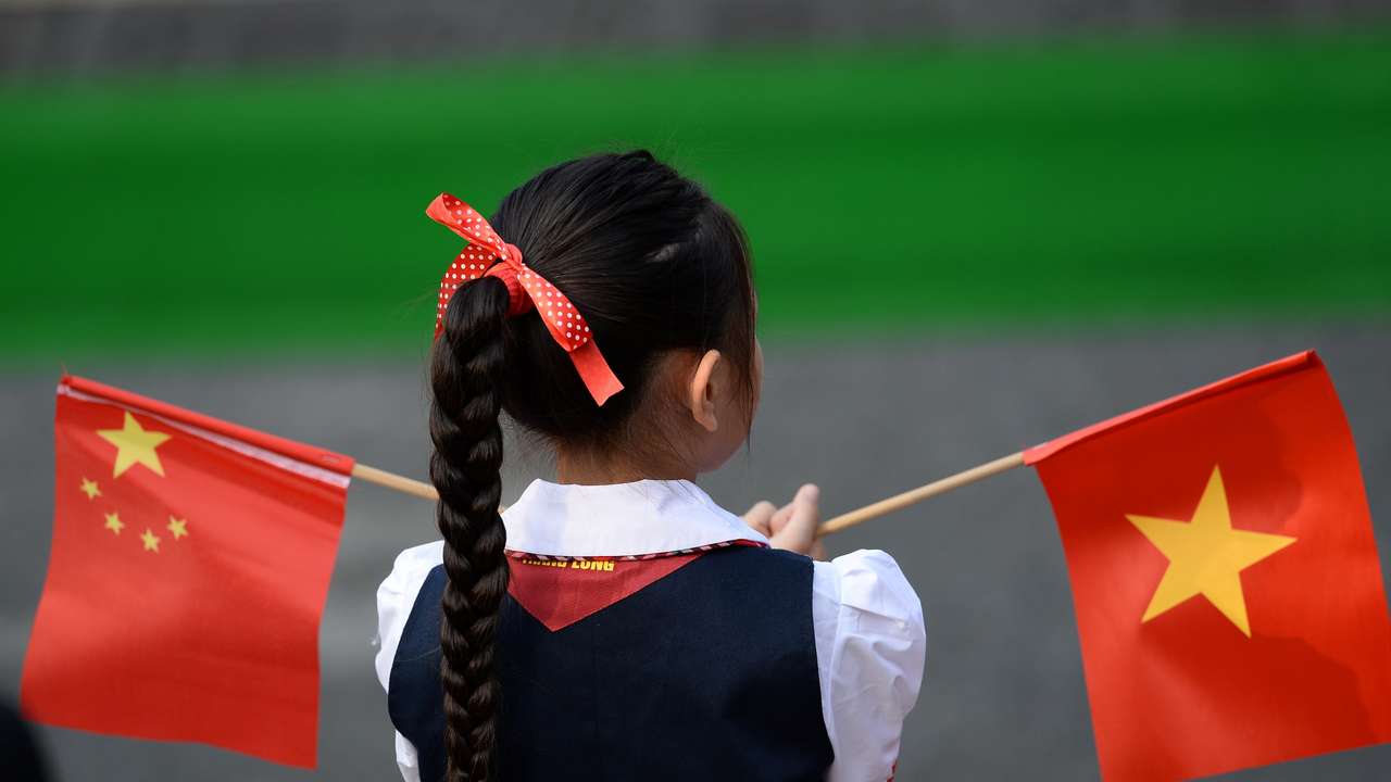 A Vietnamese pupil holds Vietnamese and Chinese flags before the welcoming ceremony at the Presidential Palace in Hanoi