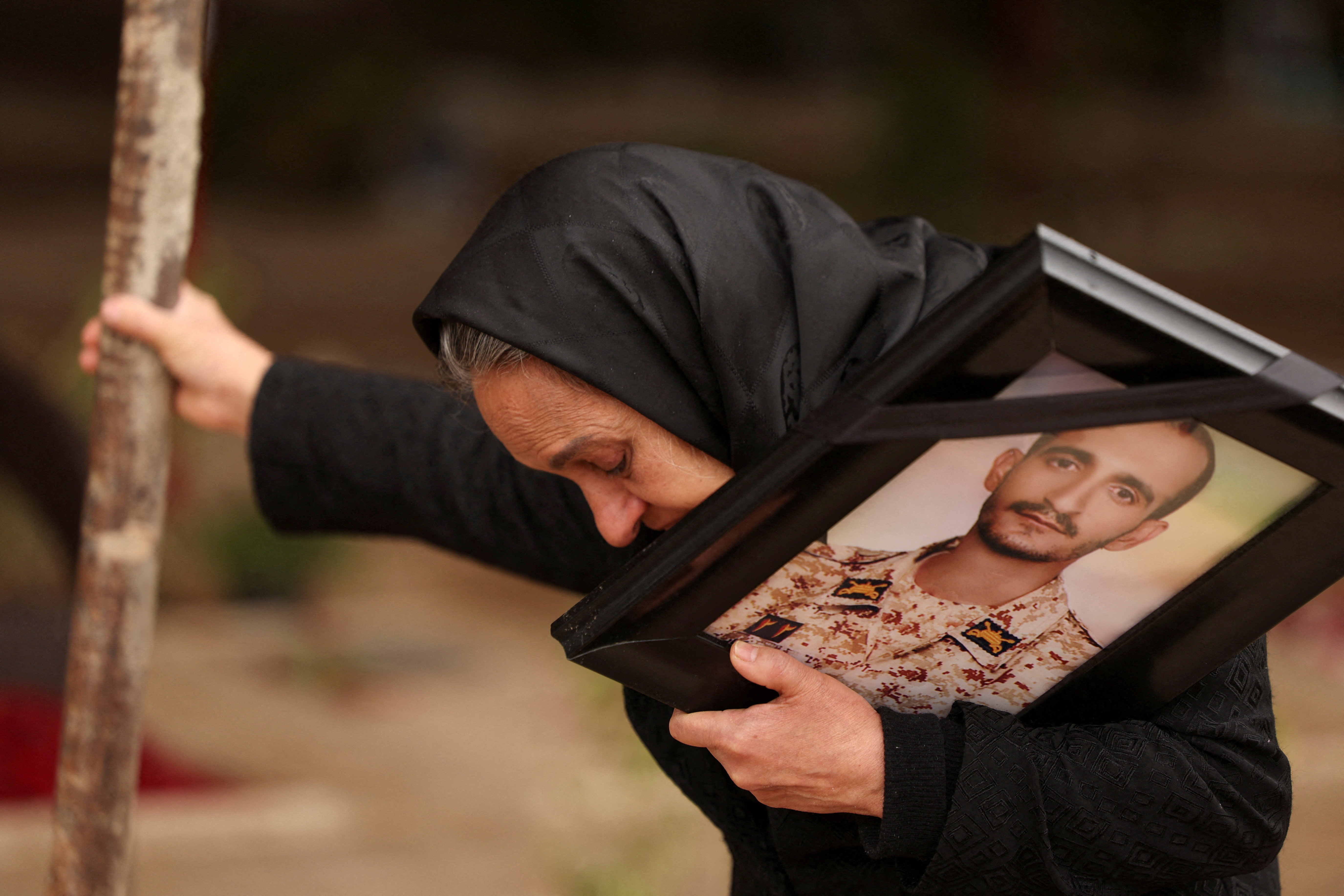 Marzia Rezaei reacts while standing near the grave of her son, Erfan, in Tehran
