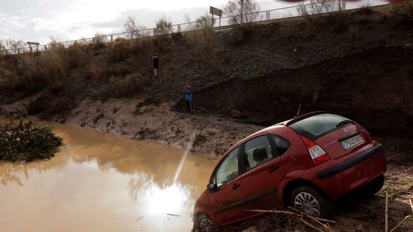 People stand in a flooded area after heavy rains and floods in Alora
