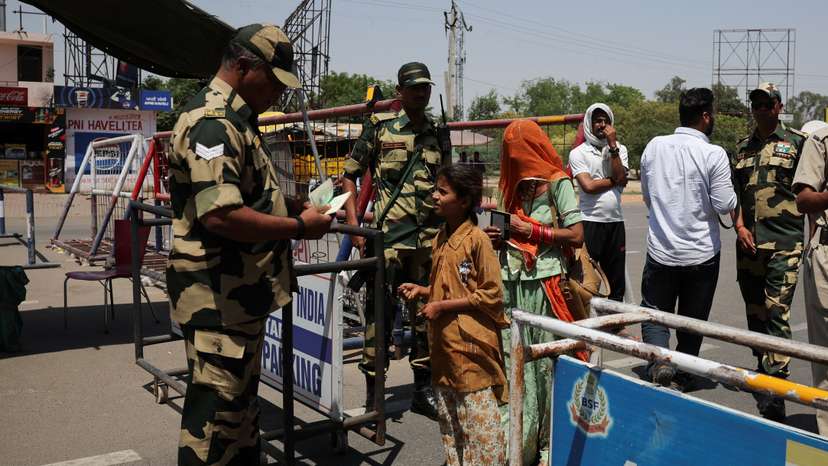 A military personnel with Border Security Force checks the passports of Pakistani citizens as they prepare to leave India, at the Attari-Wagah border crossing near Amritsar