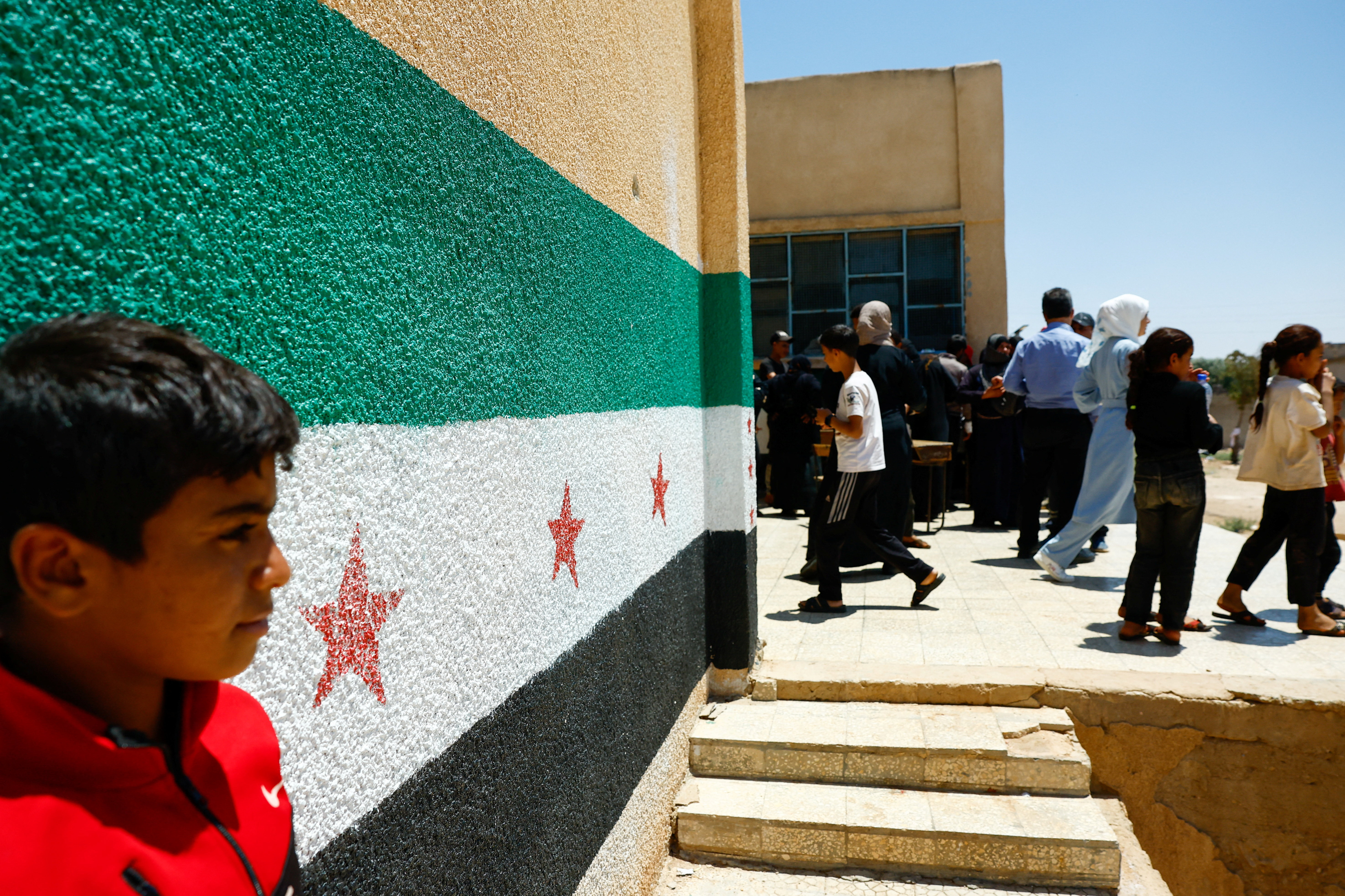 Group of Bedouin families who left Sweida walk in a school, in the village of El Sahoah