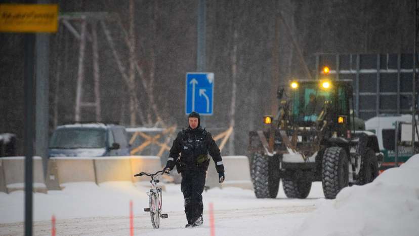 A border guard holds a bicycle of an asylum seeker at the Vartius border station in Kuhmo